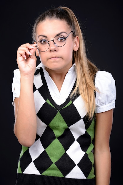 La ragazza del nerd guarda stranamente la macchina fotografica e fa una faccia.