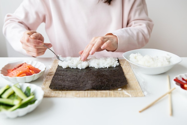 La ragazza del processo di cottura del sushi prepara sushi con gusti diversi