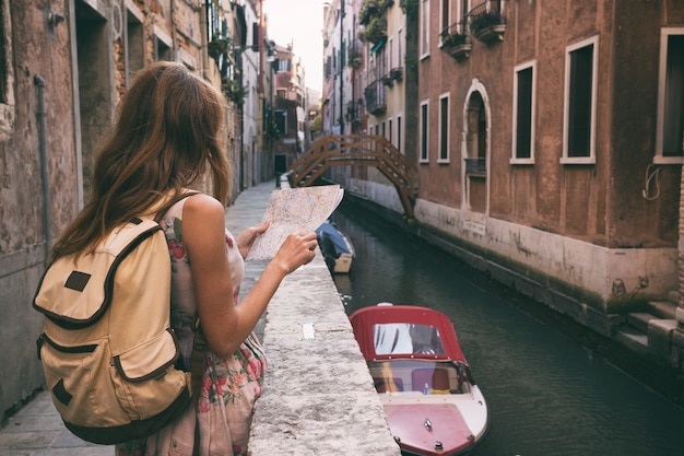 La ragazza del viaggiatore esamina la mappa di camminare a Venezia, Italia