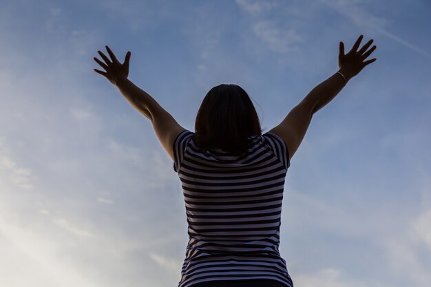 la ragazza della donna di felicità e jouful solleva la mano su in cielo sfondo