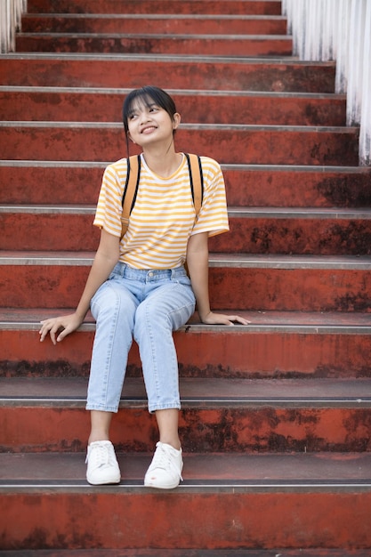 La ragazza della scuola indossa una camicia rosa e un jeans che tiene e tiene in mano un libro rosa sulle scale