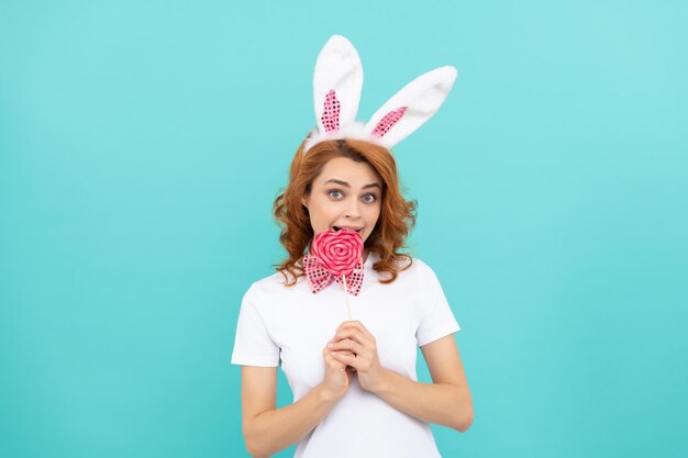 La ragazza di buona pasqua indossa le orecchie da coniglio e tiene il lecca lecca squisito