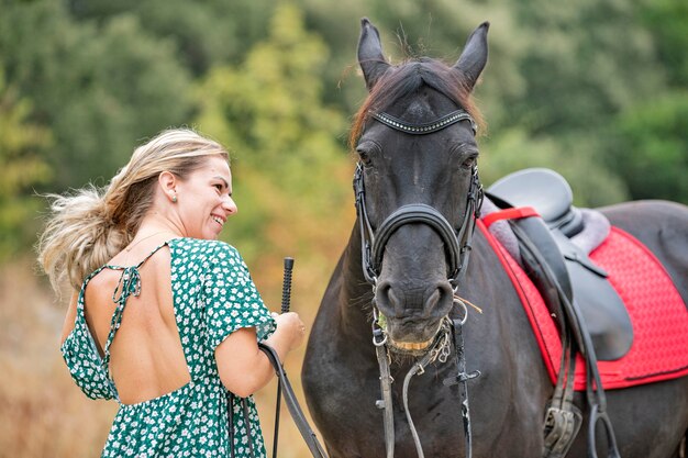 La ragazza di guida sta camminando con il suo cavallo nero