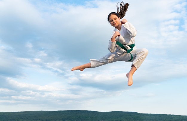 La ragazza di karate in kimono salta sul fondo del cielo