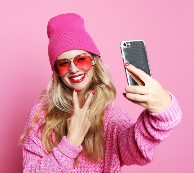 La ragazza di moda che scatta foto fa l'autoritratto sullo smartphone