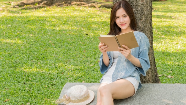 la ragazza di modo usa un libro e legge nel parco del giardino