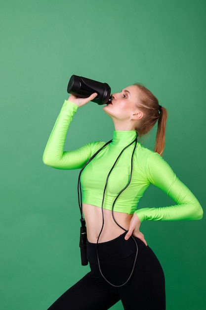 La ragazza di sport beve l'acqua dopo l'allenamento