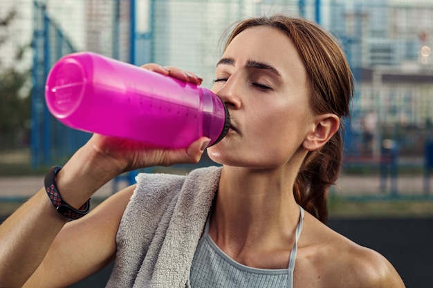 La ragazza di sport beve l'acqua dopo l'esercizio