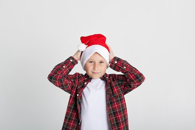 La ragazza divertente in un cappello di babbo natale mostra la classe con il suo pollice le emozioni dei bambini ritratto di un bambino su uno sfondo bianco