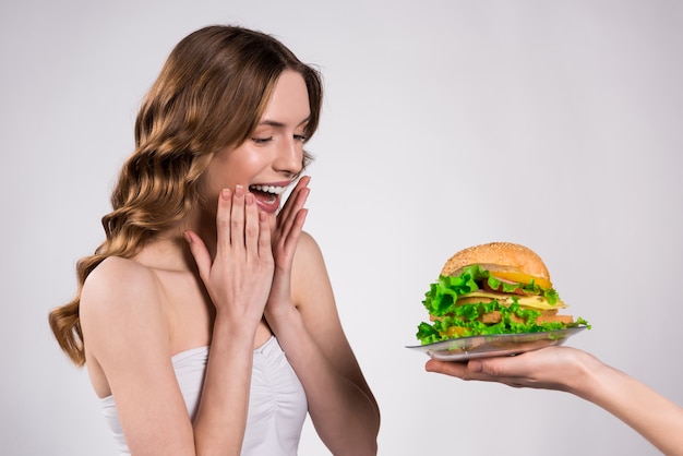 La ragazza è felice di hamburger isolato.