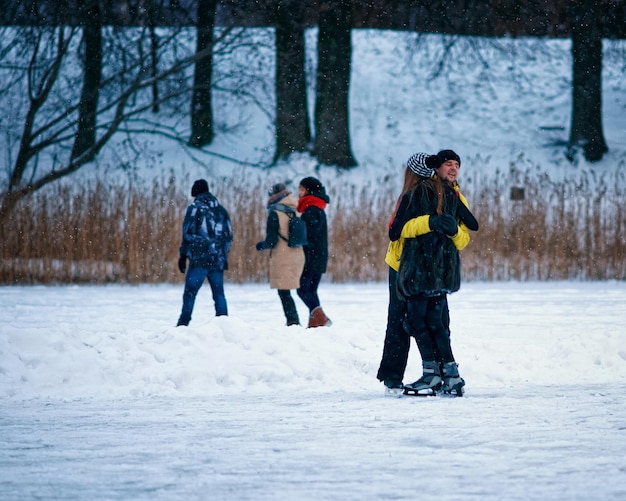 La ragazza e il compagno si abbracciano alla pista di pattinaggio invernale ricoperta di neve a Trakai, in Lituania.
