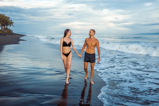 La ragazza e l'uomo camminano sulla spiaggia in costume da bagno