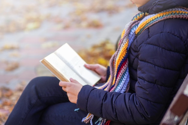 La ragazza è seduta su una panchina e sta leggendo un libro