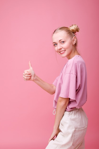 La ragazza è soddisfatta e mostra il segno con la mano sul rosa