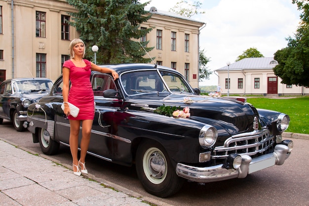 La ragazza elegante propone vicino all&#39;automobile retrò