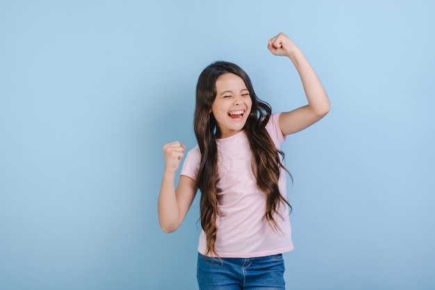 La ragazza emozionante ha sollevato le mani nel gesto di successo in studio.