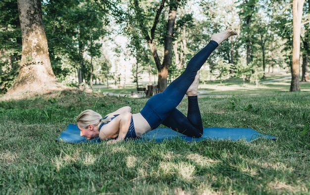 La ragazza esegue complessi esercizi di yoga nel parco all'aperto