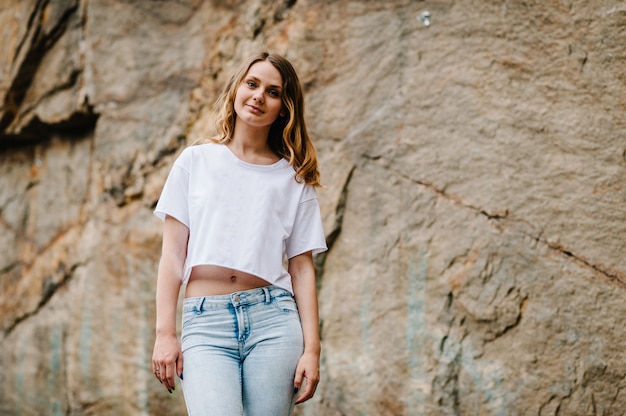 La ragazza esile sta e posa alla scogliera