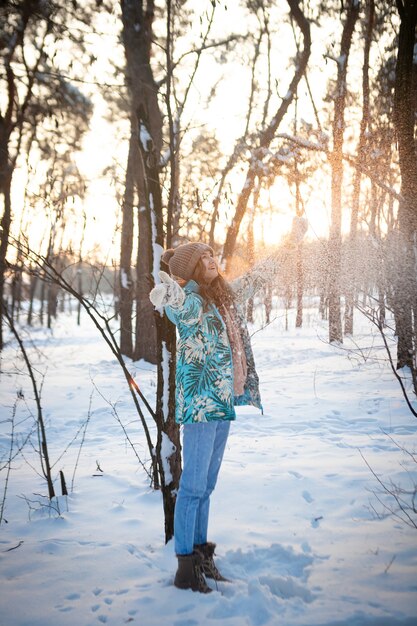 La ragazza esulta in inverno in un bosco innevato al tramonto