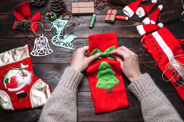 La ragazza fa i regali di Natale su un tavolo di legno scuro, decorazioni natalizie