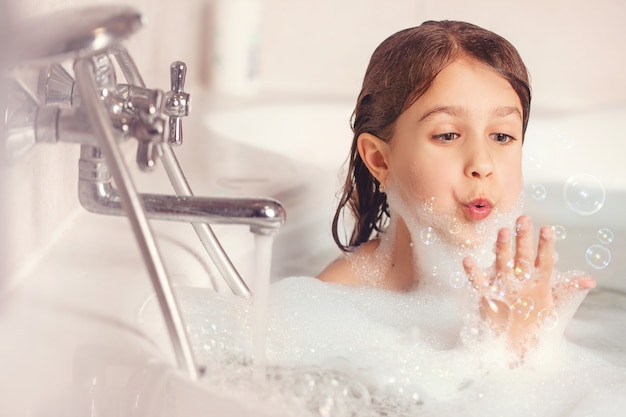 la ragazza fa il bagno e gioca con la schiuma in bagno.