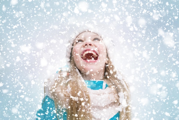 La ragazza felice apre la bocca per catturare la neve che cade