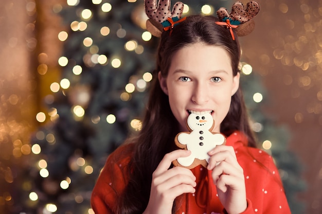 La ragazza felice con le orecchie dell'elfo tiene nelle sue mani il pan di zenzero, pupazzo di neve