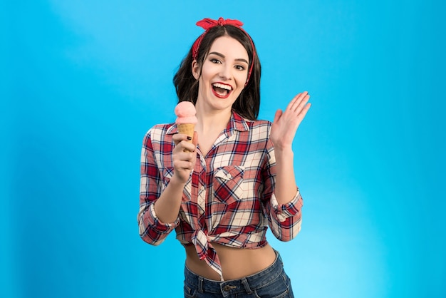 La ragazza felice con un gelato sullo sfondo blu