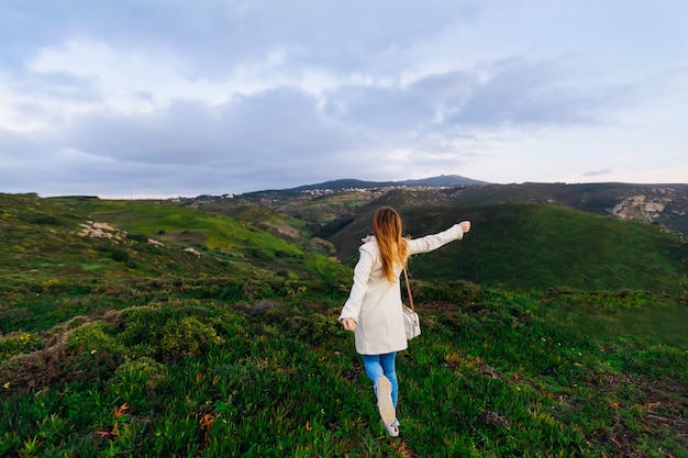 La ragazza felice corre sulle colline per le vacanze