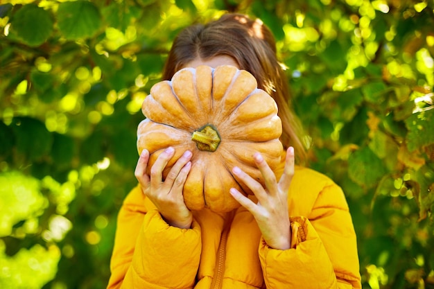 La ragazza felice del bambino copre il viso con la zucca all'aperto ad Halloween