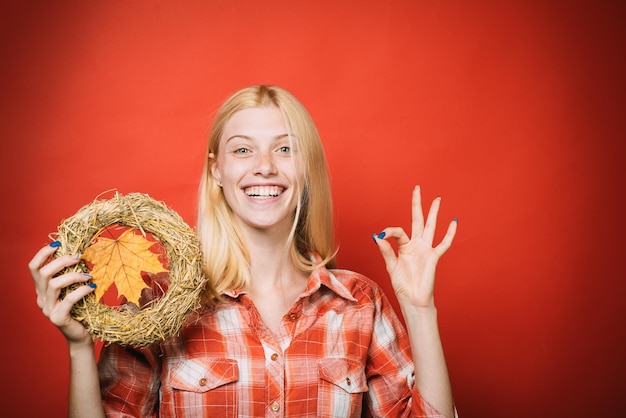 La ragazza felice di vendita di autunno con la corona di autunno mostra lo spazio della copia del segno giusto per pubblicizzare la moda autunnale