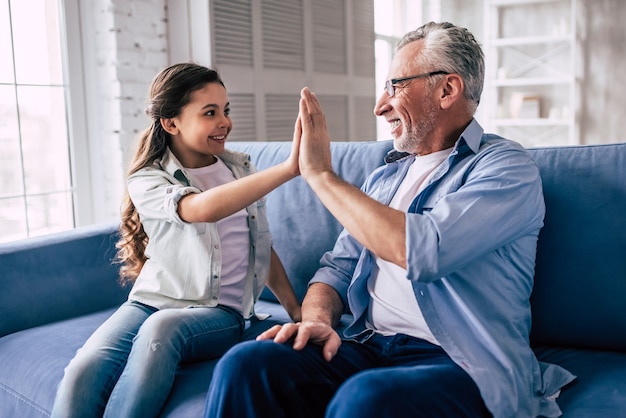 La ragazza felice e un nonno salutano sul divano