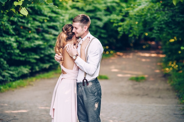 La ragazza felice emozionale si è appoggiata al suo ragazzo sullo sfondo del parco al tramonto