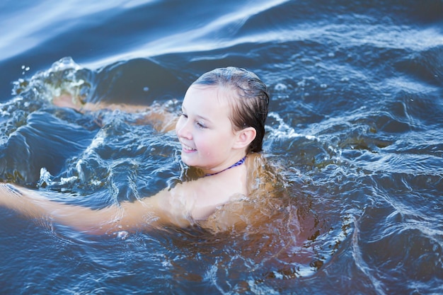 La ragazza felice nuota nell'acqua