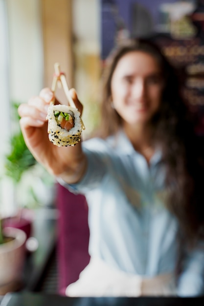 La ragazza felice sta offrendo sushi nel ristorante giapponese