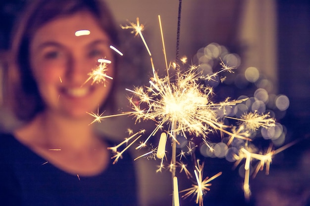 La ragazza felice sta tenendo una stella filante nel periodo natalizio