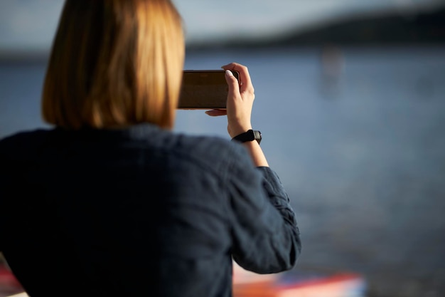 La ragazza fotografa il fiume al telefono La ragazza comunica tramite collegamento video