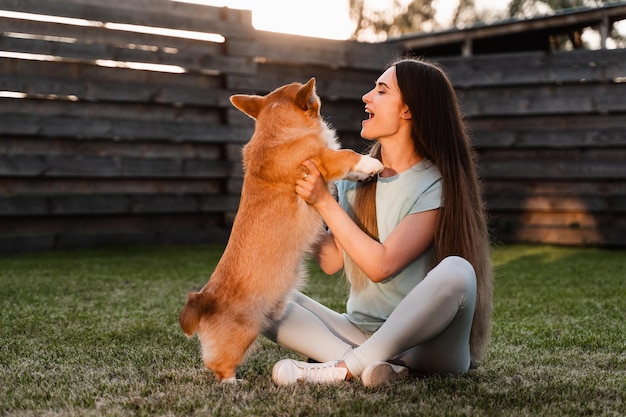 La ragazza gioca con il cane Corgi sull'erba e si diverte Playful Welsh Corgi Pembroke Lifestyle con animali domestici