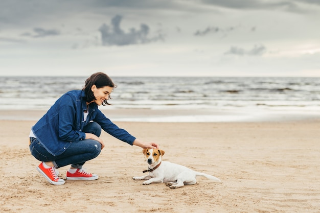 La ragazza gioca con un cane in riva al mare