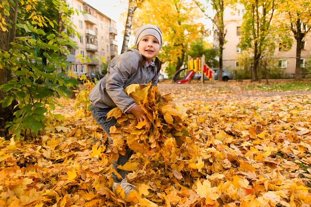 La ragazza gioca nel fogliame autunnale