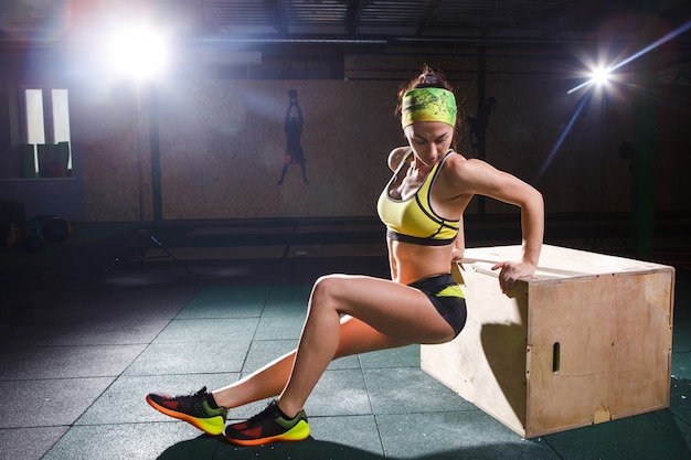 La ragazza giovane e forte salta in palestra fino all&#39;altezza. Allenamento delle gambe e cardio