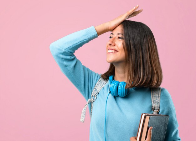 La ragazza giovane studente con maglione blu e cuffie ha appena realizzato qualcosa.