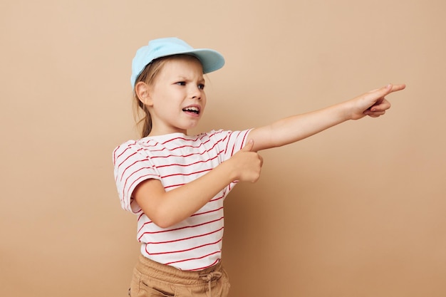 La ragazza graziosa che posa i vestiti del bambino ha isolato il fondo di divertimento