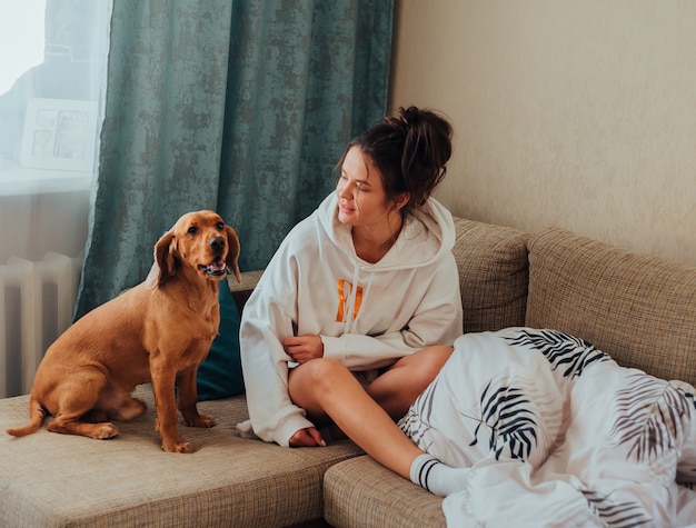 La ragazza guarda il cane che è saltato sul divano