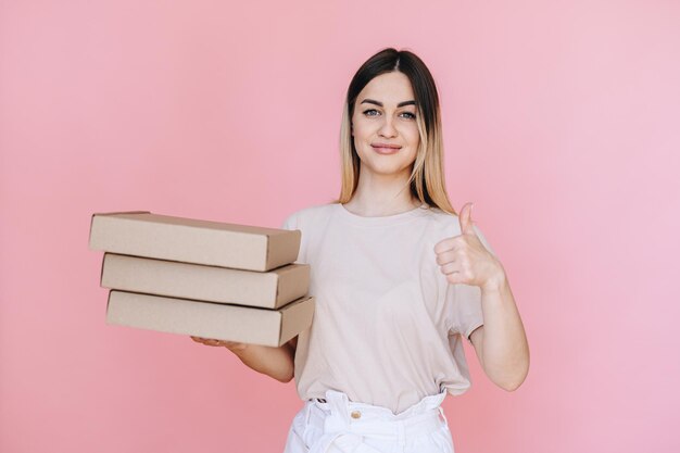 La ragazza guarda la telecamera tiene in mano scatole di pizza e mostra il pollice in alto