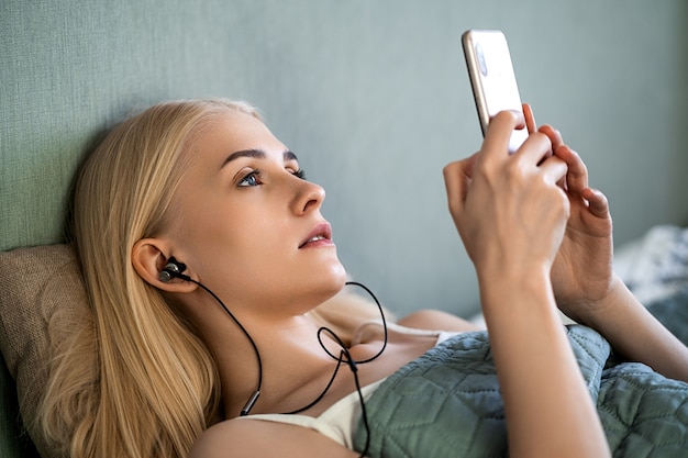 La ragazza ha auricolari neri nelle orecchie, attraverso i quali suona la musica dal suo telefono