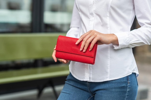 La ragazza in bianco tiene in mano un portafoglio rosso