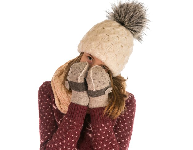 La ragazza in caldo maglione, cappello, sciarpa e guanti copriva il viso isolato su bianco