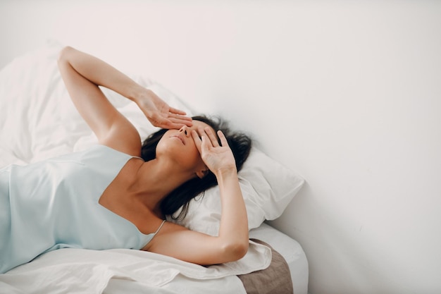 La ragazza in camicia da notte si allunga dolcemente nel suo letto