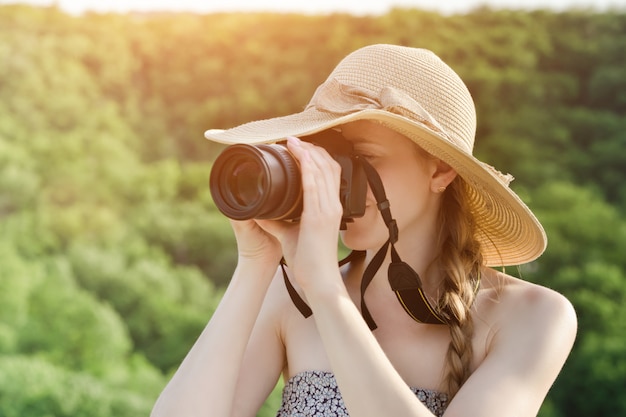 La ragazza in cappello prende le immagini sulla foresta verde. Vista laterale